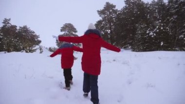 Karlı yolda koşan mutlu genç kızlar, uçuşta kollarını düzleştirme. Çam parkında çocukların temiz havasında yürüyün. Noel Tatili