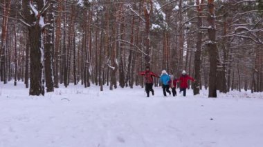 Happy family runs through snowy pine park and laugh. Children play with their parents in winter forest and smile. Relationship mom dad and daughters