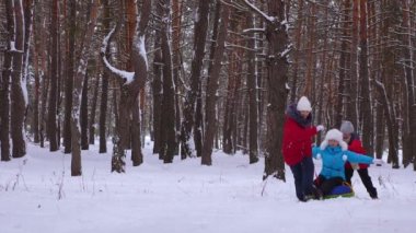 Çocuk Anne çam parkı ve gülmek karlı yol boyunca kar daire rulo. İğne yapraklı orman kışın oynama ve gülümseyerek mutlu bir aile. Anne ve kızı hafta sonu dinlenmek. Noel tatili
