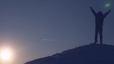 Dağ tepe fethetti adam yüksek karlı dağ dalgalar üzerinde duran ellerini kullanıyor ve zaferle gün batımında sevinir. Turist dağlar kavram hiking. Dağlarında seyahat. Soğuk koşulları