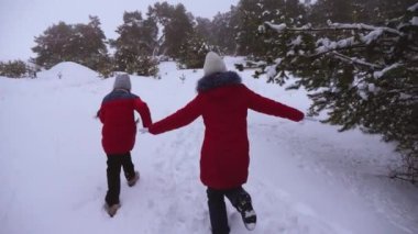 Mutlu çocuklar eğlenceli karlı kış yolda bir çam parkı içinde kış soğuk gününde çalışan. Gençler yakalamak iğne yapraklı kış ormandaki oynamak. Hava buz gibi oyunlarda. Noel tatili