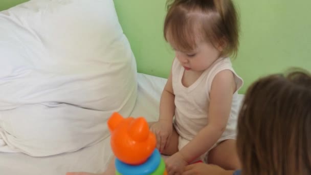 Pequeño bebé juega cubos suaves y pirámide en la sala de hospital. Los niños juegan con juguetes multicolores. Desarrollo de la edad preescolar infantil — Vídeos de Stock