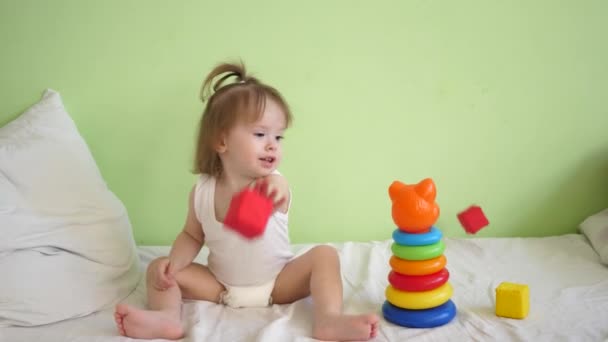 Petit enfant se remet dans les installations médicales, assis sur le lit et jouer dans des cubes doux colorés et pyramide et sourires. Récupération d'un enfant à l'hôpital — Video