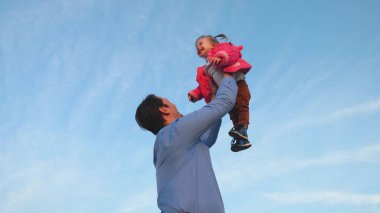 baba bebek mavi gökyüzüne attılar. Baba bebek atar. mutlu aile kavramı. Baba kızını parkta oynuyor.