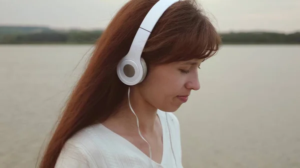 Mädchen mit Kopfhörer läuft mit Tablet am Strand entlang und hört Musik, Mädchen checkt E-Mails auf Tablet online, Nahaufnahme — Stockfoto