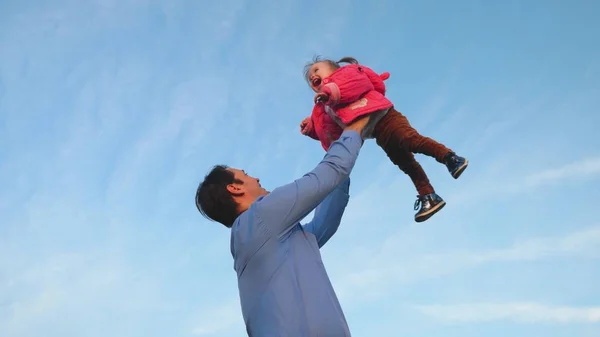 Papa warf Baby in den blauen Himmel. Papa wirft Baby hoch. Konzept der glücklichen Familie. Papa spielt mit seiner Tochter im Park. — Stockfoto