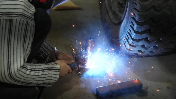 Welder connects metal parts to complex structures using electric welding. colorful sparks fly to the side — Stock Photo, Image
