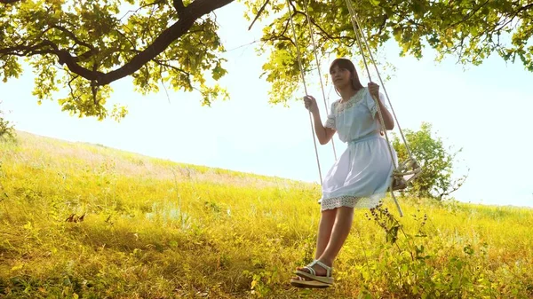 Jeune fille aux cheveux longs balançant sur une balançoire sous un chêne . — Photo