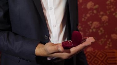 Altın elbiseli adam elinde yüzük. damat onun altın alyans el kutusunda tutar.