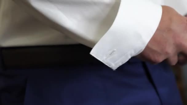 Man in een wit overhemd zet gordel op zijn broek. Close-up. de mens krijgt gekleed voor werk in de ochtend. — Stockvideo
