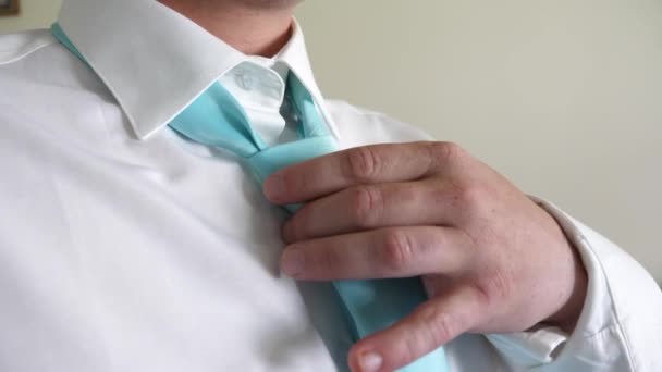 Empresario se pone corbata turquesa con las manos a camisa blanca por la mañana yendo a trabajar. Concepto de empleado de negocios. Código de vestimenta. El hombre se viste para el trabajo por la mañana. Primer plano — Vídeo de stock