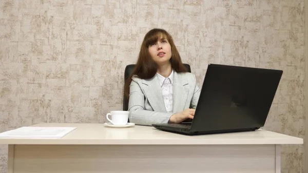 Mädchen im Büro am Schreibtisch, die am Computer arbeitet und spricht. Jungunternehmerin kommuniziert mit Kunden. Geschäftsfrau arbeitet in ihrem Büro. — Stockfoto
