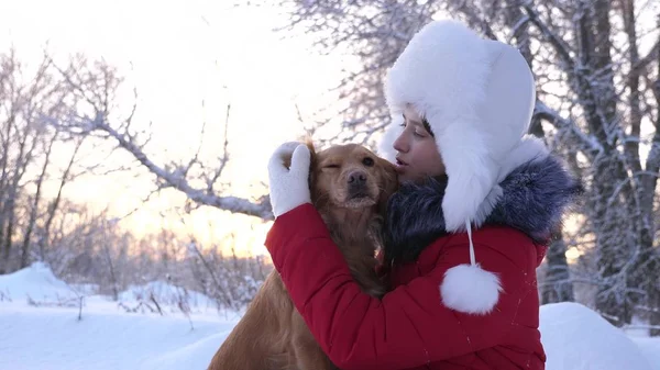 Güzel kız gülümsüyor, sevgili köpek kış aylarında parkta okşamalarla. kız bir av köpeği ile kışın Ormanda yürür. köpek hostes kisses. — Stok fotoğraf