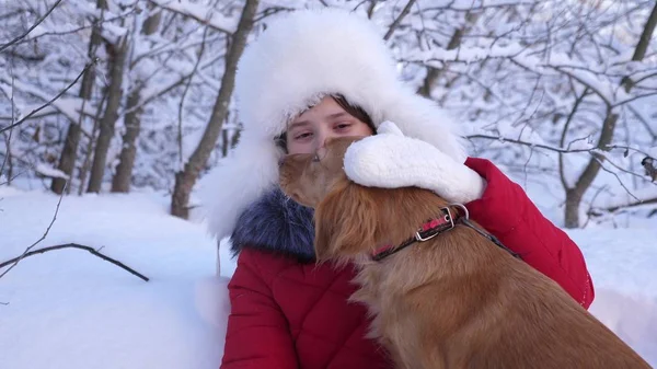 Hund leckt Mädchen Gesicht. schöne Mädchen lächelt, streichelt ihren geliebten Hund im Winter im Park. Mädchen mit Jagdhund geht im Winter im Wald spazieren. Hund küsst Gastgeberin. — Stockfoto
