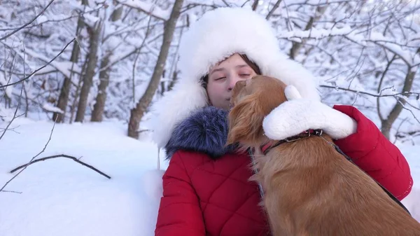 Hund leckt Mädchen Gesicht. schöne Mädchen lächelt, streichelt ihren geliebten Hund im Winter im Park. Mädchen mit Jagdhund geht im Winter im Wald spazieren. Hund küsst Gastgeberin. — Stockfoto