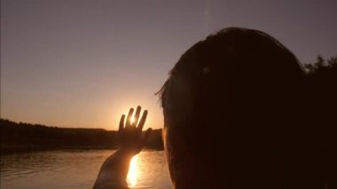 Kız nehirde durgunluk ve güneş elini uzatır. günbatımı Nehri üzerinde. dokunaklı Childs'ın el güneşe