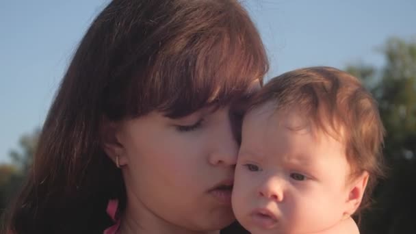 Mãe beija bebê contra o céu azul . — Vídeo de Stock