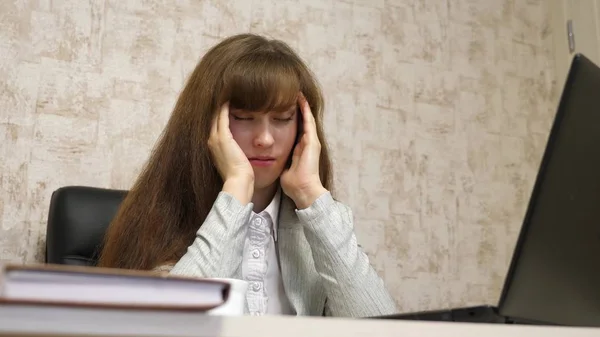 Vacker flicka sitter i stol med huvudvärk i office för laptop. trött ung kvinnlig entreprenör fungerar på datorn. Hennes ögon och huvudet värker. överarbetade anställda på kontoret. — Stockfoto