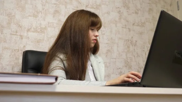 Schönes Mädchen, das im Bürostuhl sitzt und am Computer tippt und spricht. junge Geschäftsfrau arbeitet am Computer. — Stockfoto