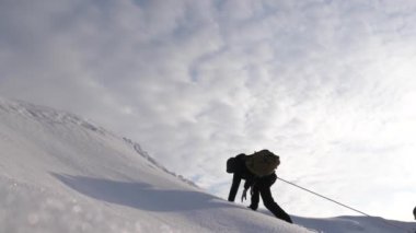 Seyahat etmek güçlü bir rüzgar karda yokuş yukarı onların zafer halat tırmanmaya. turistlerin kışın birlikte zorluklar üstesinden takım olarak çalışırız. Kışın üç Alpenists ip üzerinde dağa tırmanmak..