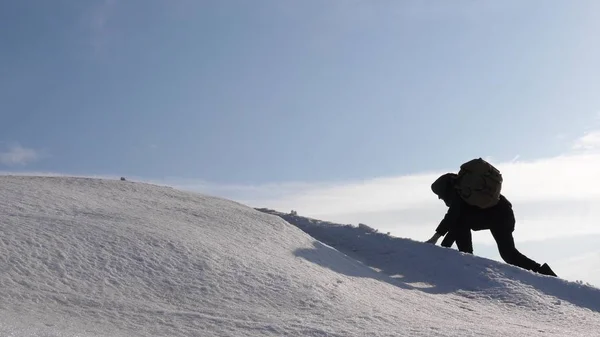 Hand in Hand erklimmen Bergsteiger den Gipfel eines schneebedeckten Berges. Das Reiseteam im Winter geht an sein Ziel, Schwierigkeiten zu überwinden. gut koordinierter Teamwork-Tourismus. — Stockfoto