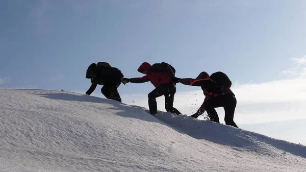 Dağcılar bir karlı dağın tepesine tırmanmaya el içinde el. Kışın gezginlerin takımı zorlukların üstesinden amaçları için gidin. iyi koordineli çalışması turizm. — Stok fotoğraf