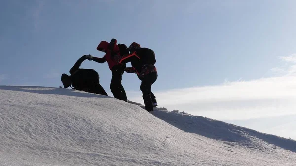 Альпинисты рука об руку поднимаются на вершину снежной горы. Команда путешественников зимой идет к своей цели преодоления трудностей. хорошо скоординированный командный туризм . — стоковое фото