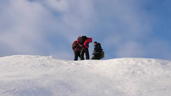 Команда альпинистов зимой готовится спуститься по канату с горы. Путешественники спускаются по веревке со снежного холма. слаженная командная работа в сфере зимнего туризма . — стоковое фото