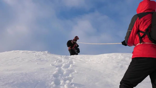 Los alpenistas se unen en invierno bajando la cuerda de la montaña. Los viajeros descienden por cuerda desde una colina nevada. turismo de trabajo en equipo bien coordinado en invierno —  Fotos de Stock