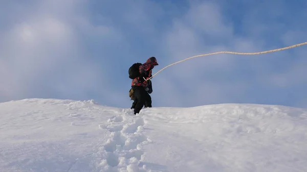 Путешественники спускаются по веревке со снежного холма. Альпинисты зимой спускаются по канату с горы. хорошо скоординированный командный туризм зимой — стоковое фото