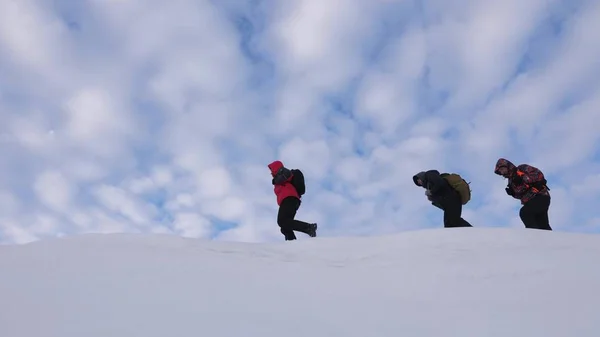 Путешественники следуют друг за другом вдоль снежного хребта. Команда альпинистов зимой поднимается на вершину горы. хорошо скоординированный командный туризм зимой — стоковое фото