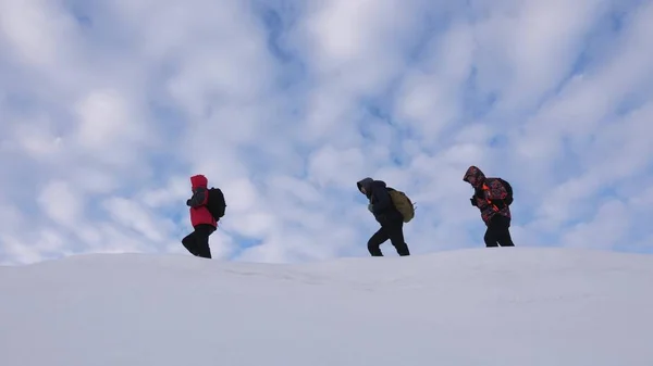 Los viajeros se siguen unos a otros a lo largo de la cordillera nevada. El equipo de alpenistas en invierno va a la cima de la montaña. turismo de trabajo en equipo bien coordinado en invierno —  Fotos de Stock
