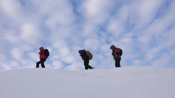 Les voyageurs se suivent le long de la crête enneigée. Alpenists équipe en hiver aller au sommet de la montagne. un tourisme d'équipe bien coordonné en hiver — Photo