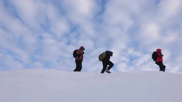 teamwork people in difficult conditions. climbers team in winter go to top of the mountain. Travelers follow one another along snowy ridge. well-coordinated teamwork tourism in winter