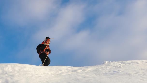 No inverno o alpinista prepara-se para descer na corda da montanha. Os viajantes caminham ao longo do topo da colina nevada com corda. turista no inverno no pólo norte . — Vídeo de Stock