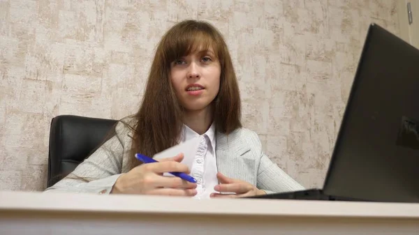 Vacker flicka sitter i en stol på kontoret och prata och att göra anteckningar i bloknot. ung kvinnlig entreprenör som arbetar med en klient i ett kontor — Stockfoto