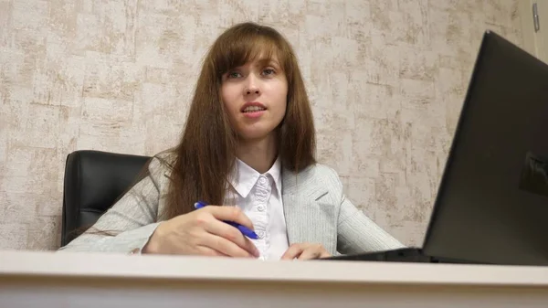 Belle fille assise dans une chaise dans le bureau et parler et prendre des notes dans bloknot. jeune femme entrepreneure travaillant avec un client dans un bureau — Photo