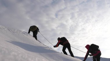 Seyahat etmek güçlü bir rüzgar karda yokuş yukarı onların zafer halat tırmanmaya. turistlerin kışın birlikte zorluklar üstesinden takım olarak çalışırız. Kışın üç Alpenists ip üzerinde dağa tırmanmak..