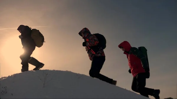 Team von Geschäftsleuten auf Sieg und Erfolg. Teamarbeit der Geschäftsleute. Drei Bergsteiger klettern nacheinander auf einen schneebedeckten Hügel. Menschen arbeiten zusammen, um Schwierigkeiten zu überwinden. — Stockfoto