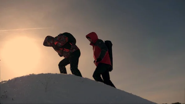 ビジネス人のチームは、勝利と成功に移動します。ビジネス人々 のチームの仕事です。3 つの登山は、雪に覆われた丘の上に別の後に 1 つを登る。困難を克服するために共同作業します。. — ストック写真