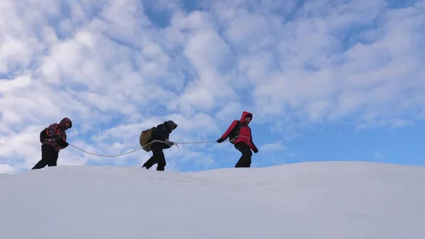 Mit Seilen gebundene Bergsteiger folgen einander entlang des schneebedeckten Grats. Team von Reisenden im Winter auf den Gipfel des Berges zu gehen. Gut koordinierter Teamwork-Tourismus im Winter — Stockfoto