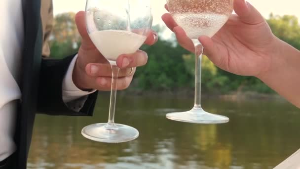 Trabajo en equipo de una pareja amorosa. champán brilla y espumas al sol. celebrando el éxito y la victoria. Vierte vino espumoso de una botella en copas de vino transparentes. Moción lenta — Vídeo de stock