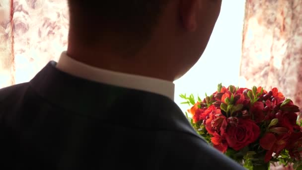 Hermoso ramo de rosas rojas en las manos del hombre con chaqueta y camisa blanca. Primer plano. hermosas flores en las manos del hombre un regalo para su amada mujer. novio con flores — Vídeo de stock
