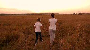 mutlu çocuk el ele tutuşarak tarlada yürümek. Çocuk kulaklık müzik dinlemek ve gün batımında oynuyorum. mutlu çocukluk kavramı.