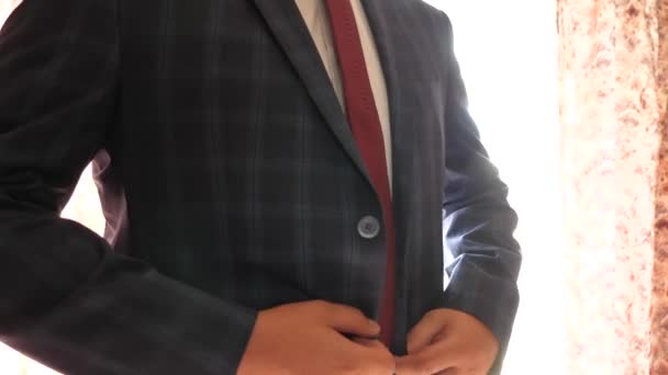 Man knop omhoog zijn knoppen op zijn jas, close-up. zakenman zet op een blauwe jas in een kooi. kantoor werknemer krijgt gekleed in de ochtend. concept van stijlvolle en modieuze kleding voor mannen — Stockvideo