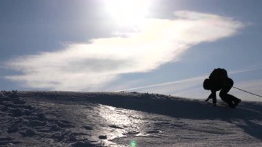 ekip çalışması kazanmak arzusu. Dağcılar bir ip üzerinde tepenin üst tırmanmak bir arkadaşa yardım. Kışın yolcuları güneşin parlak ışınları bir tepe üzerinde silüeti. spor turizmi kavramı.