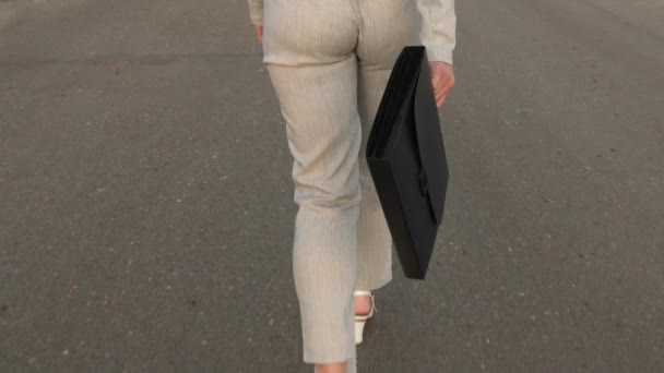 Femme d'affaires sensuelle avec de longues jambes marchant sur la route. Gros plan. femme d'affaires marche sur la route avec une mallette noire à la main . — Video