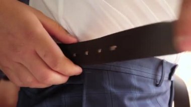 Beyaz gömlekli işadamı pantolonunda kemer koyar. yakın çekim. adam sabah işe için giyinmiş alır. ofis çalışanı sabah giyinmiş.