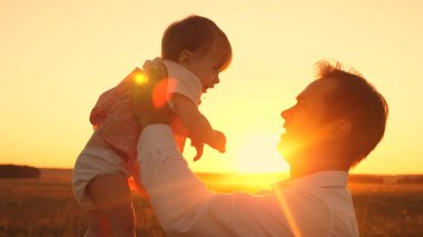 Güzel kızım baba gülücükler parlak gün batımında elinde. Mutlu baba bebek Parkı ile bir yaz akşamı oynarken.