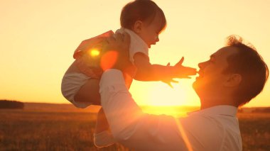 Güzel kızım baba gülücükler parlak gün batımında elinde. Mutlu baba bebek Parkı ile bir yaz akşamı oynarken.
